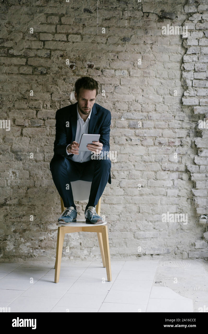Empresario sentado en una silla con tablet Foto de stock