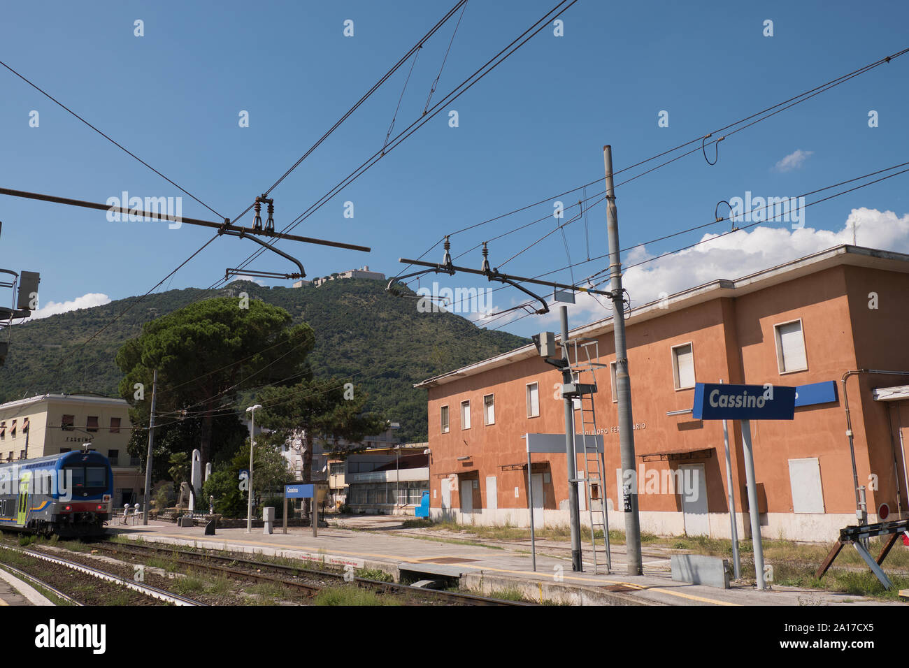 Tren regional en Cassino railway station en summerwith monasterio de Montecassino en la distancia, Italia Foto de stock