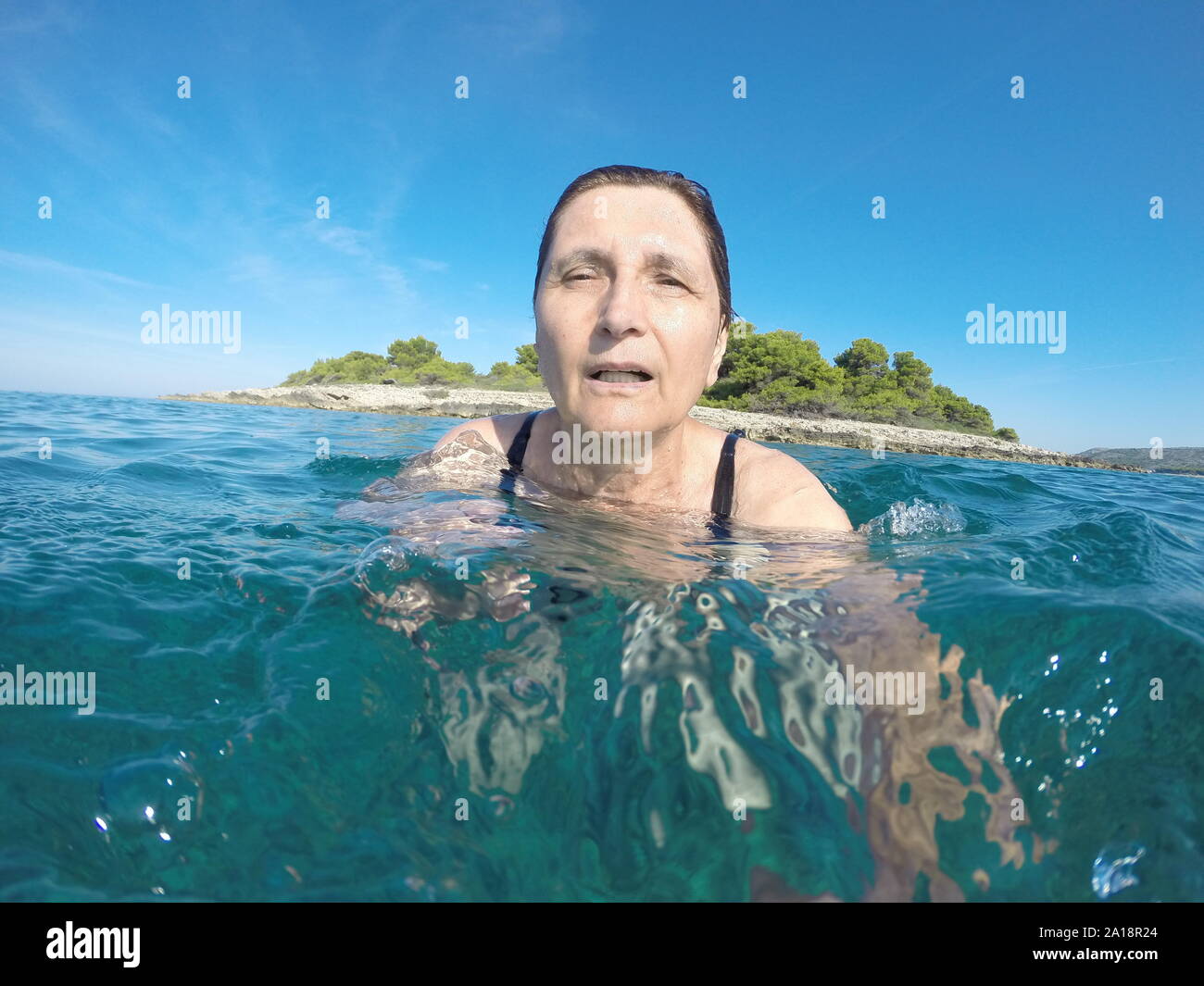 Mujer madura, nadando en el azul claro del mar Adriático Foto de stock