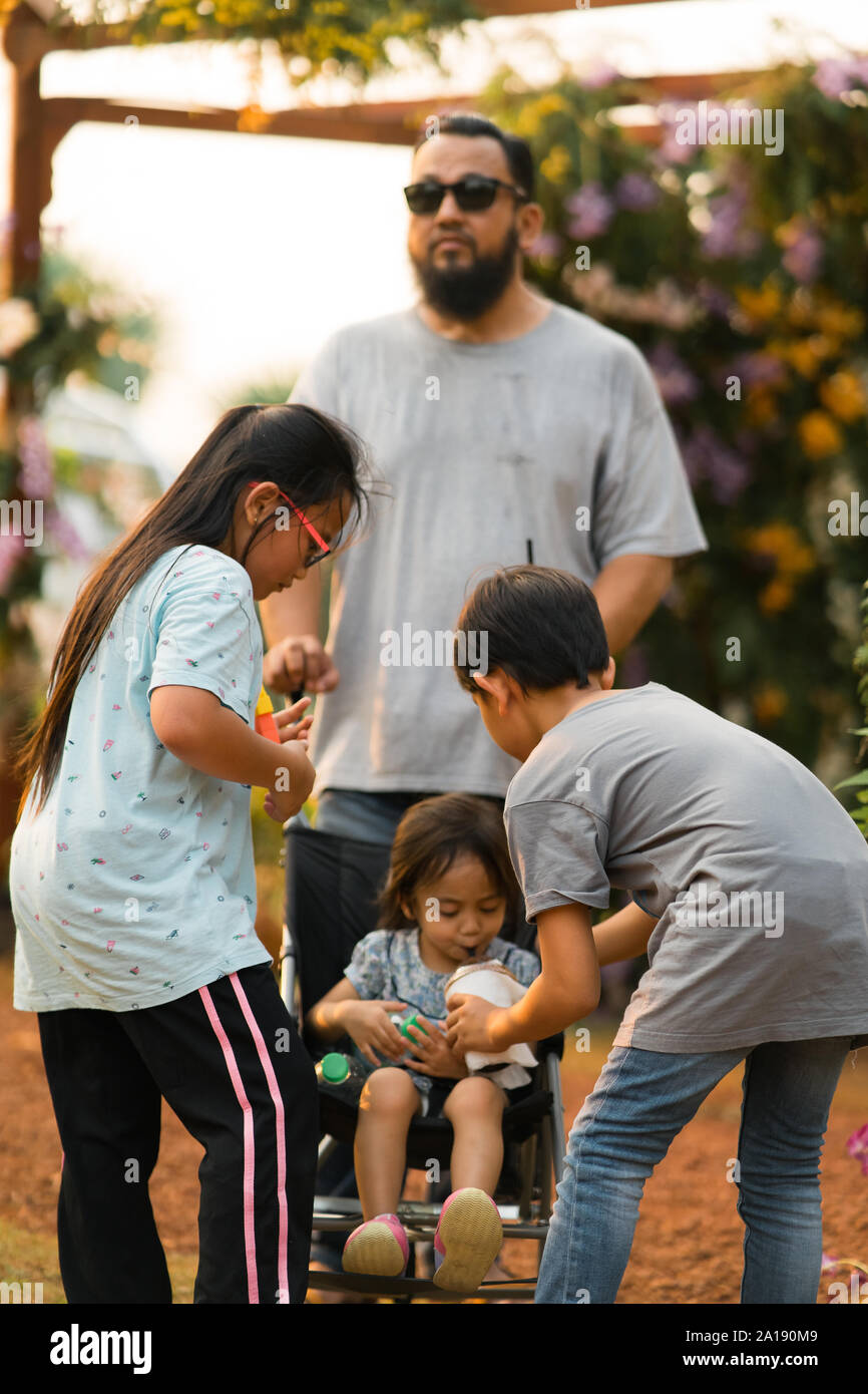 Familia de Asia en el parque. Niño bebiendo de hermano. Foto de stock