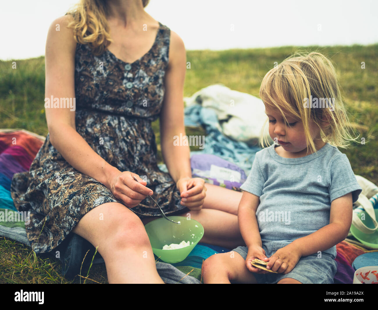 Una joven madre y su hijo están teniendo un picnic en la hierba Foto de stock