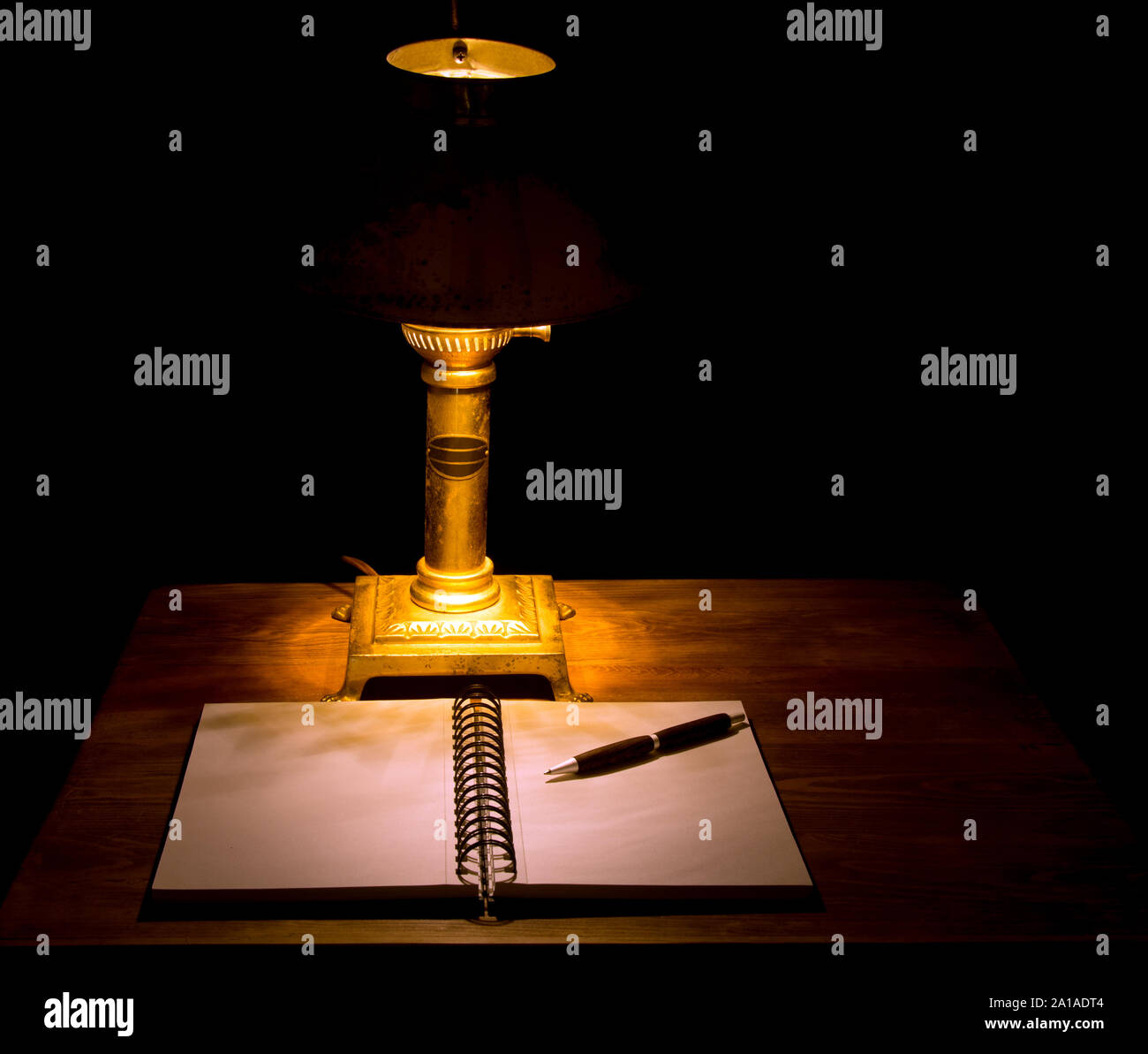 Moody, imagen oscura de un portátil con un lápiz sobre una mesa de madera, iluminada por una lámpara vintage antiguo Foto de stock