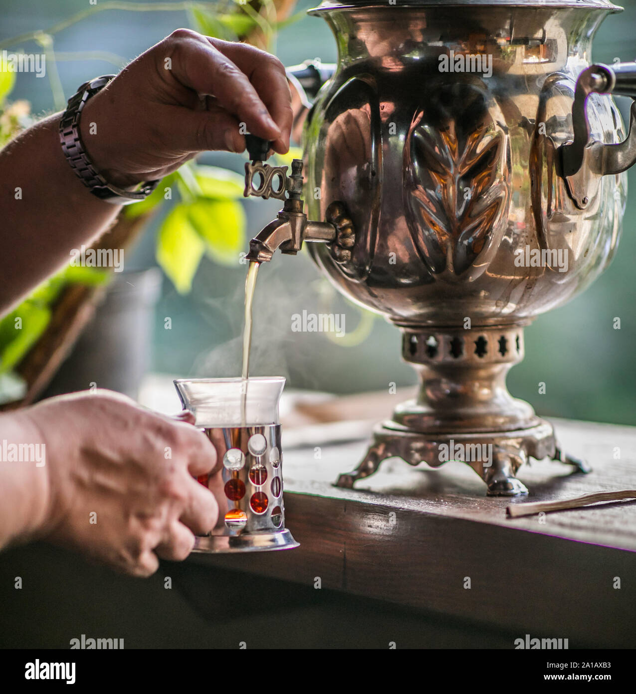 El hombre está vertiendo agua desde tradicionales del metal viejo samovar ruso. La hora del té. Foto de stock