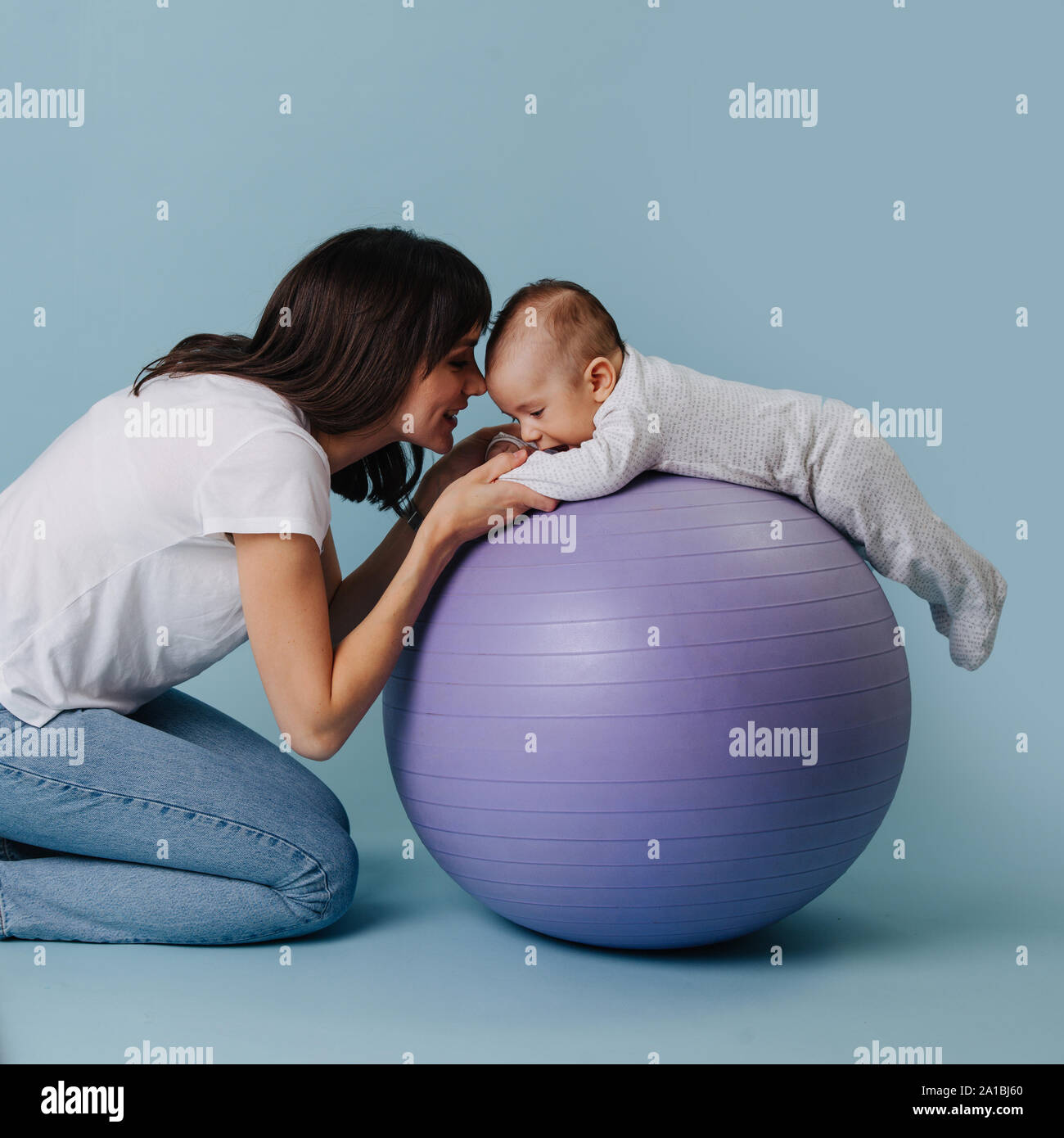 Feliz Madre Haciendo Ejercicios Con Su Nino Pequeno Bebe Sobre Purpura Bola Del Yoga Fotografia De Stock Alamy