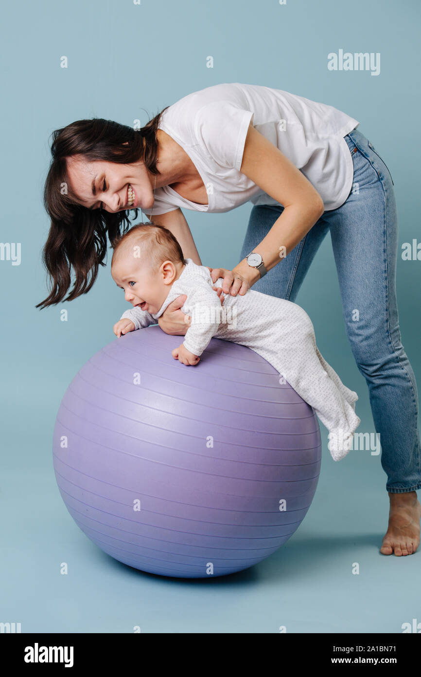 Feliz Madre Haciendo Ejercicios Con Su Nino Pequeno Bebe Sobre Purpura Bola Del Yoga Fotografia De Stock Alamy