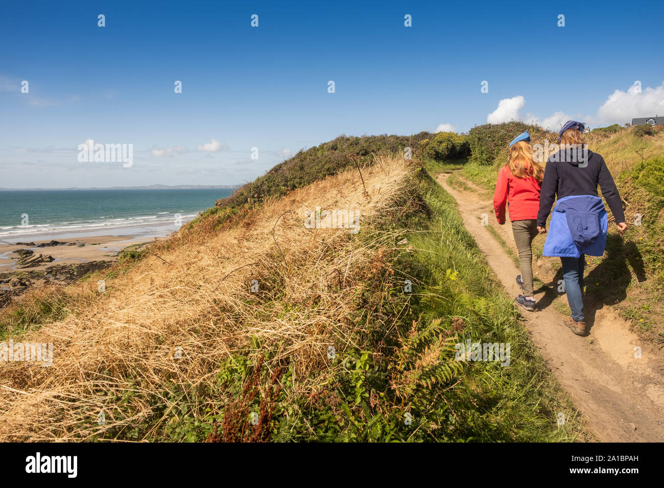 La gente caminando a lo largo de la ruta costera cerca de amplio refugio en la costa de St Bride's Bay, el Parque Nacional de Pembrokeshire, al sur de Gales Occidental UK Foto de stock