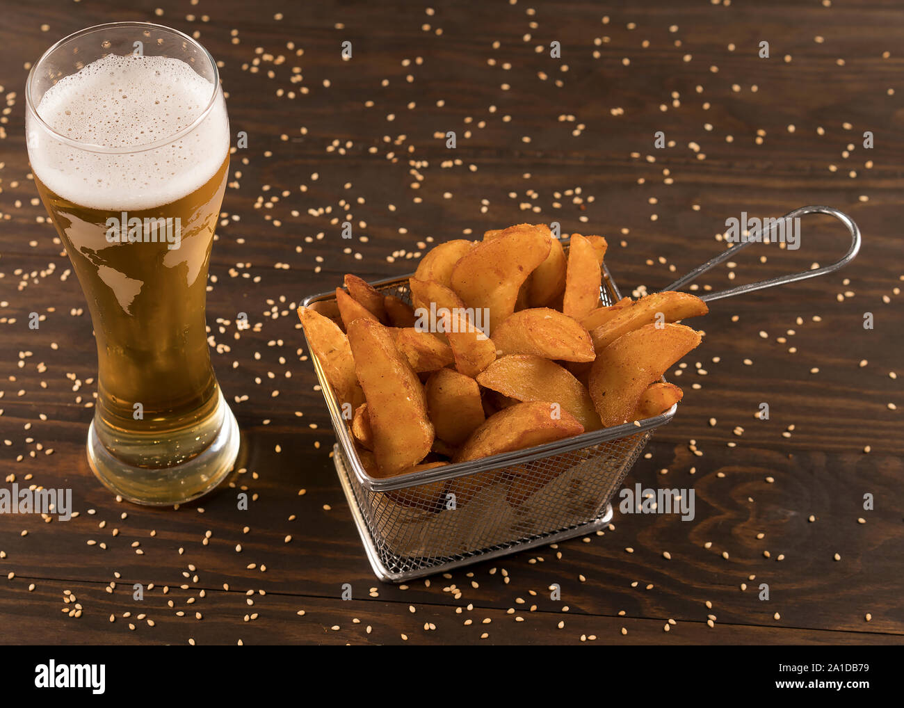 Patatoe cuñas en la canasta metálica con cerveza Foto de stock