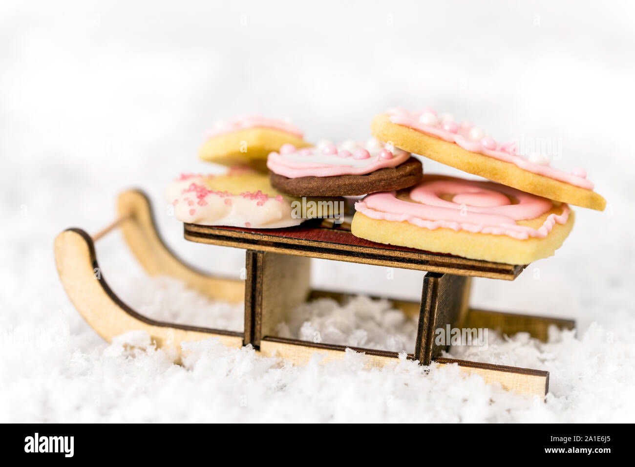 Rosa galletas de Navidad en un trineo de madera, fondo blanco, concepto de panadería y temporada de invierno Foto de stock