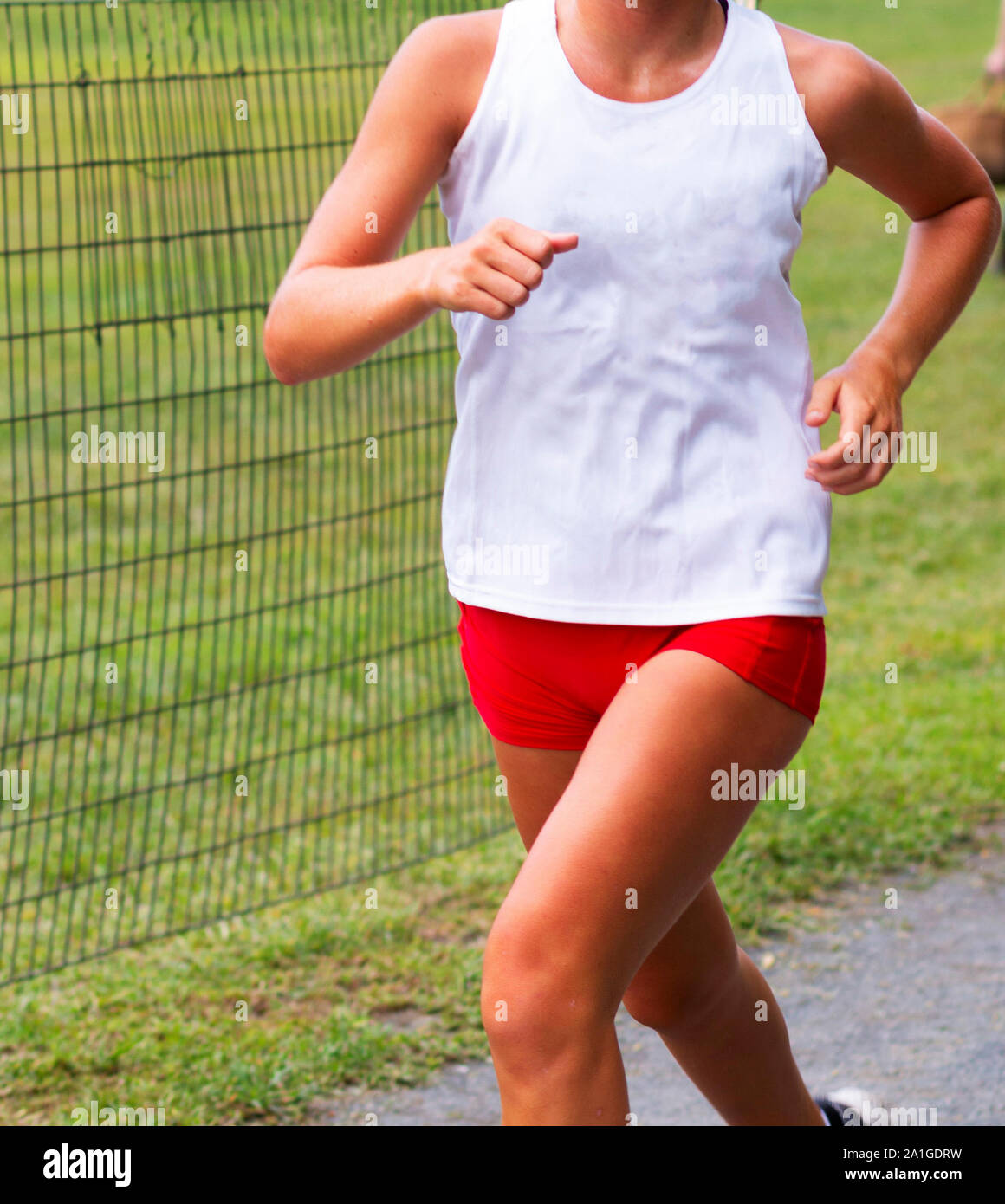 Cierre de una niña de escuela superior que llevaba un top blanco y  apretados calzones rojos corriendo en una carrera de cross country  Fotografía de stock - Alamy