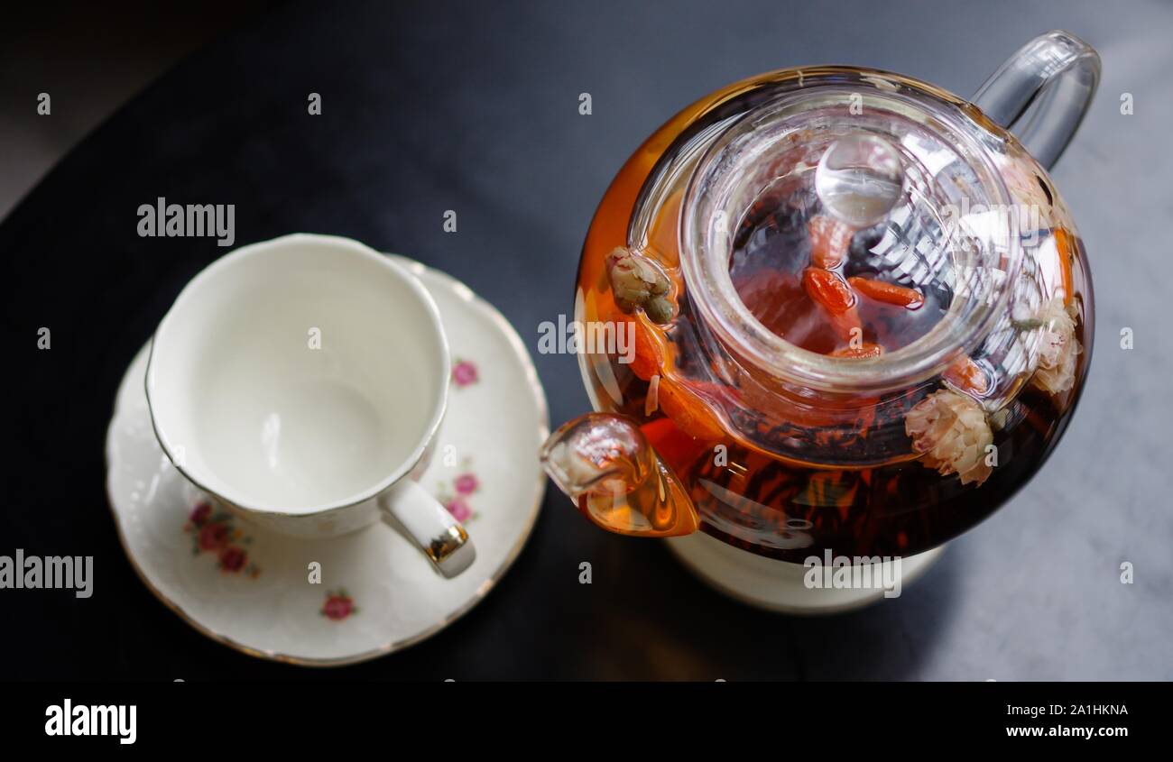 Tetera de cristal transparente con té negro y taza de té vacía