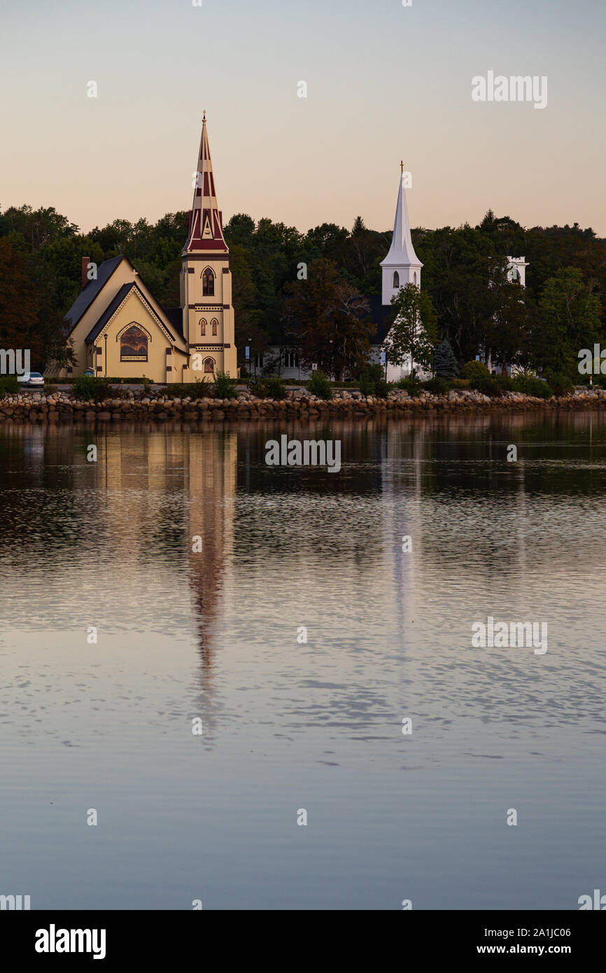 Tres iglesias a lo largo de la orilla del mar en Mahone Bay, reflejada en el agua en el amanecer de un bello día. Foto de stock