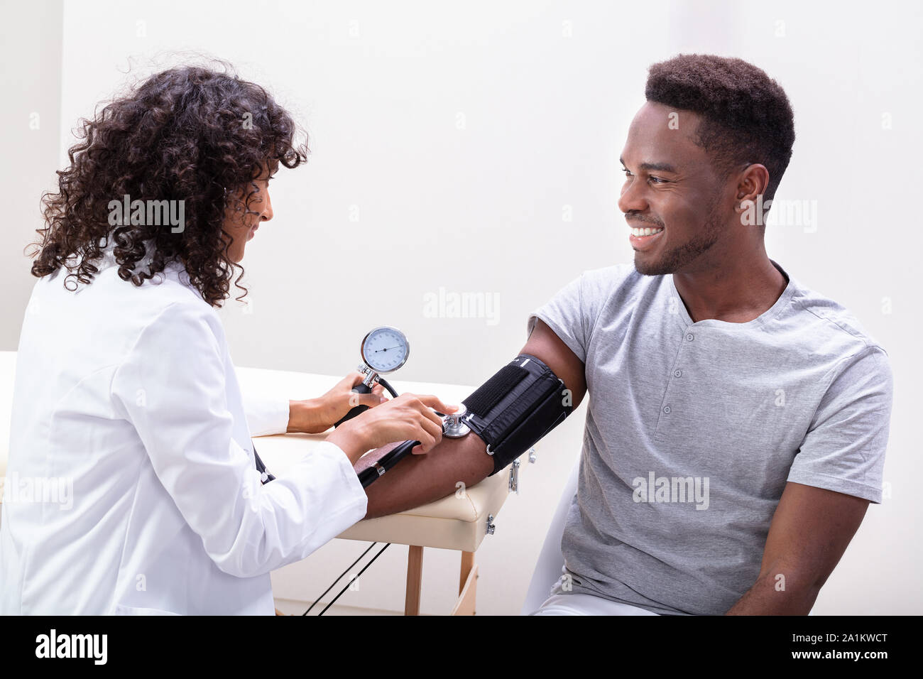 Cerca de la mano del médico femenino el chequeo de la presión arterial Foto de stock