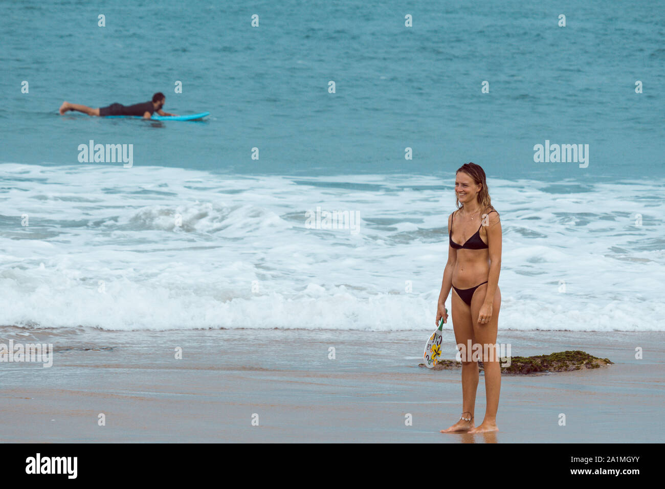 Arugam Bay, Sri Lanka - 09/15/2019 - Blanco bikini negro desgastado jugando pong en la playa. Mientras tanto, surfista intentando una ola Fotografía de stock - Alamy