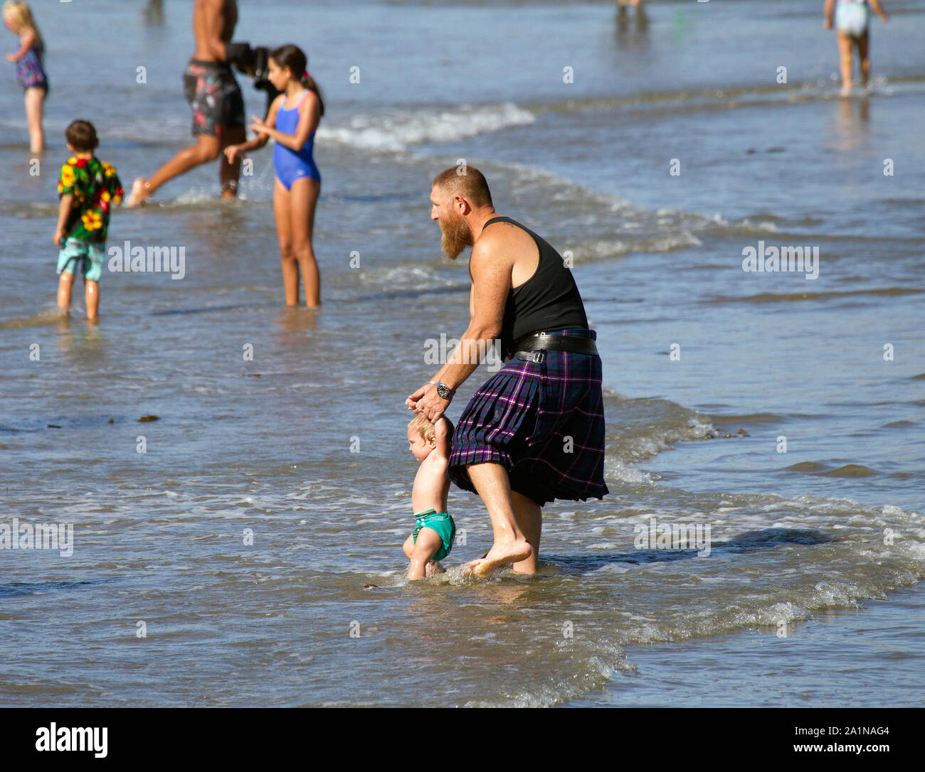 Hombre en Falda tomados de la mano del niño en el océano Foto de stock