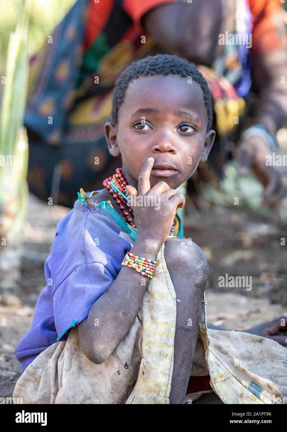 El lago Eyasi, Tanzania, 11 de septiembre de 2019: hadzabe kid con su madre mientras ella está cavando tubérculos para cenar Foto de stock