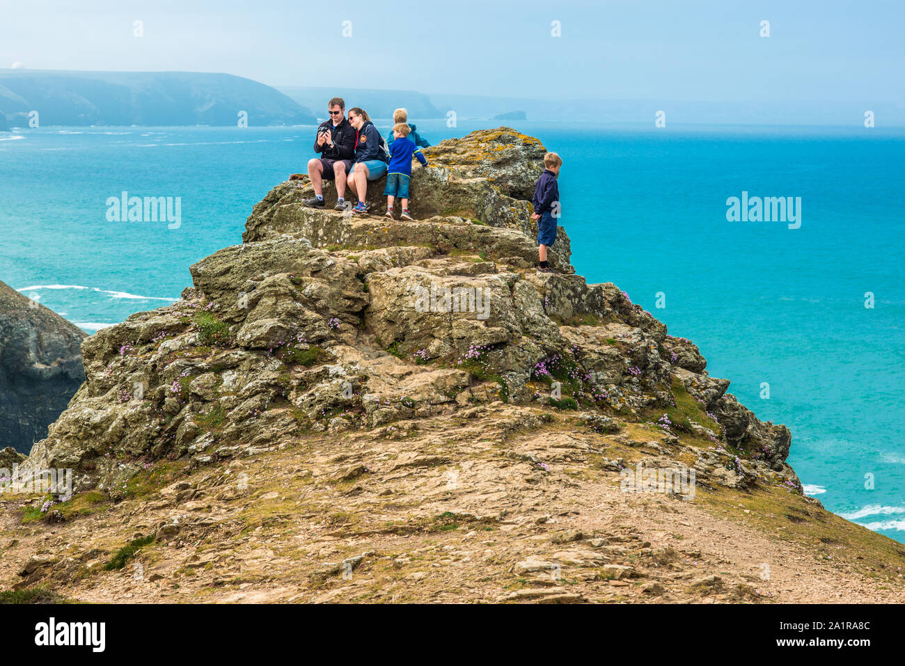 Una familia en las rocas por encima de la Capilla Santa Inés Porth en la costa de la herencia en Cornwall, Inglaterra, Reino Unido. Foto de stock