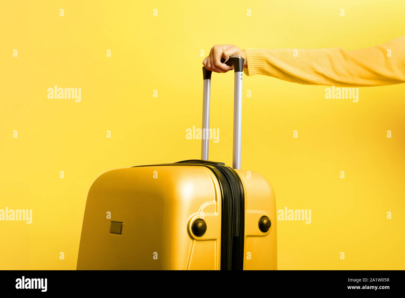 Mujer sosteniendo en la mano una maleta de color amarillo sobre fondo  amarillo, el concepto de viaje Fotografía de stock - Alamy