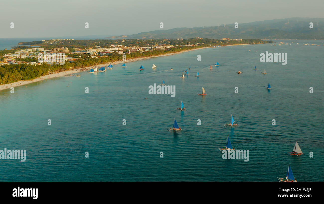 Vista aérea de los yates de vela en la playa de arena de la Isla Boracay en el ocaso del tiempo. Playa blanca tropical con velero. Concepto de vacaciones de verano y viajes. Foto de stock