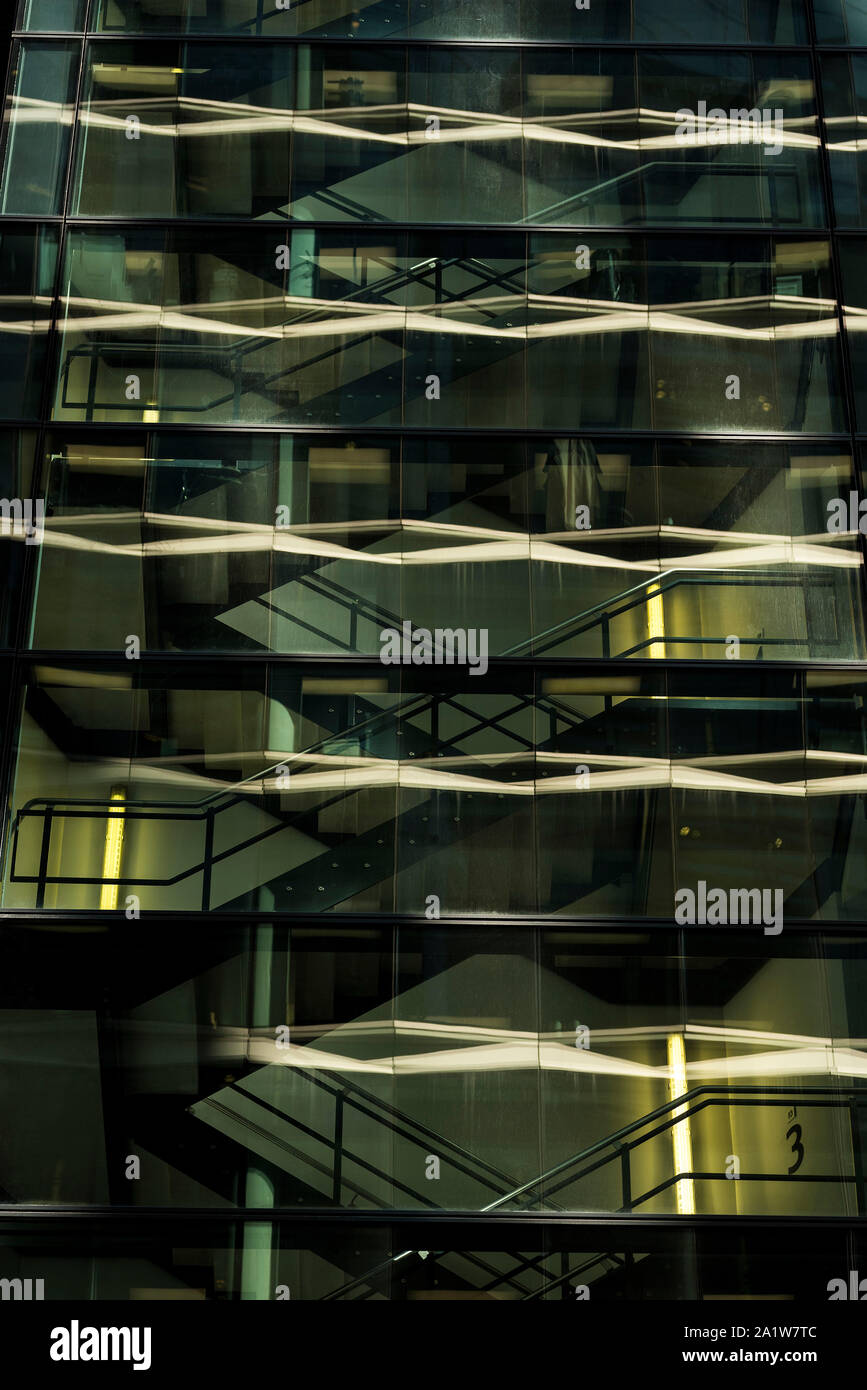 Los reflejos en el cristal frontal de un edificio alto, edificio de oficinas de cristal y acero. Foto de stock