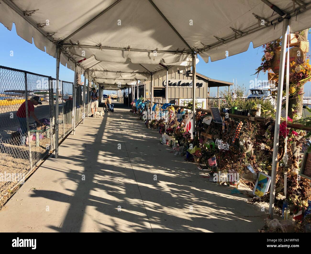 En Santa Bárbara, California, Estados Unidos. 28 Sep, 2019. Memorial por las víctimas de botes de buceo perdido en el mar sigue firme y transformar en el mar barco de desembarco dock, en el Puerto de Santa Bárbara, donde la concepción se albergaban antes del Día del Trabajo accidente que mató a 34 personas en tres días de vacaciones a las Islas del Canal de la Mancha. Las familias y amigos de los fallecidos han visitado el sitio ritual durante tres semanas, procedentes de países tan lejanos como Singapur y la India con sus seres oneÃs cenizas y fotos. Una compañía de cruceros recientemente puso en marcha un cerco y toldo, y los turistas son curiosos y reverente mientras caminan b Foto de stock