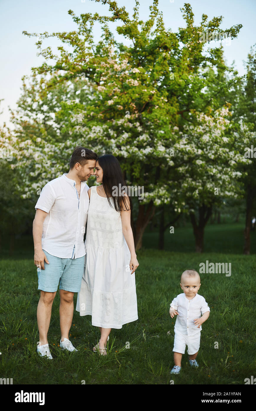 Hermosas jóvenes padres, elegante guapo en pantalones cortos y camisa y  belleza morena en el vestido blanco y su pequeño hijo lindo divertirse  cerca Fotografía de stock - Alamy