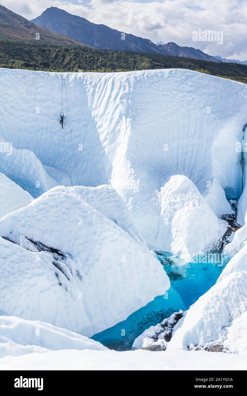 Escalador de hielo haciendo su camino hacia arriba de un cañón entre roto el hielo del Glaciar Matanuska. Escalada en Hielo vertical profunda en el desierto de Alaska. Foto de stock