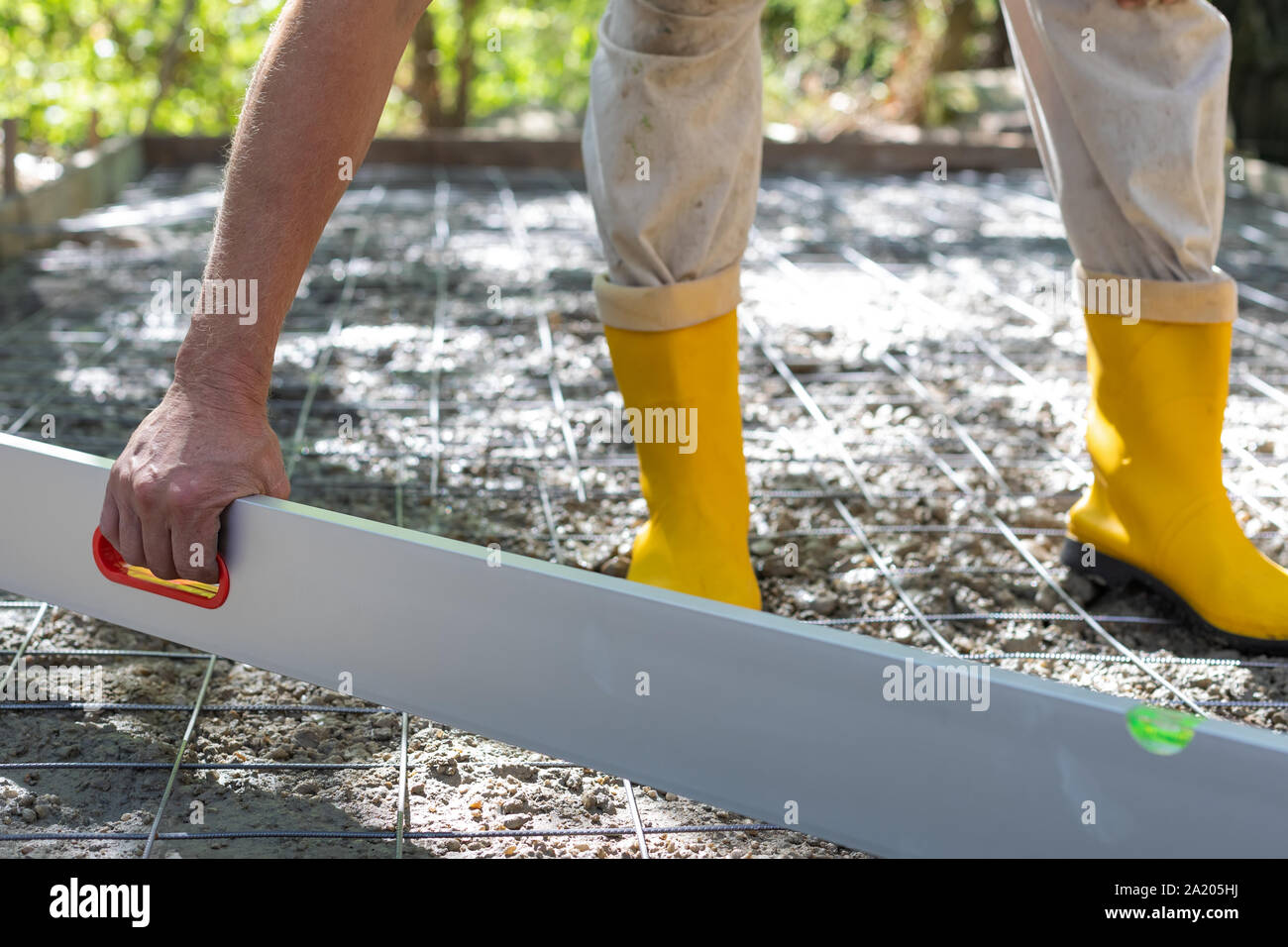 Trabajador de la construcción en amarillo botas de goma en el sitio de  construcción, enderezar y suavizar el hormigón Fotografía de stock - Alamy