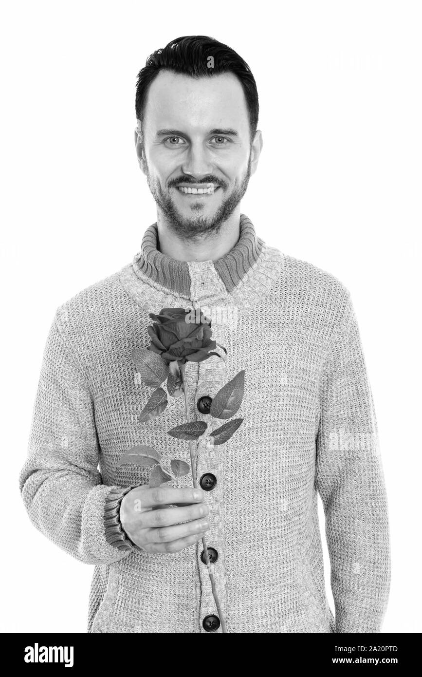 Foto de estudio de feliz joven sonriente sujetando rosa roja listos para el día de San Valentín Foto de stock