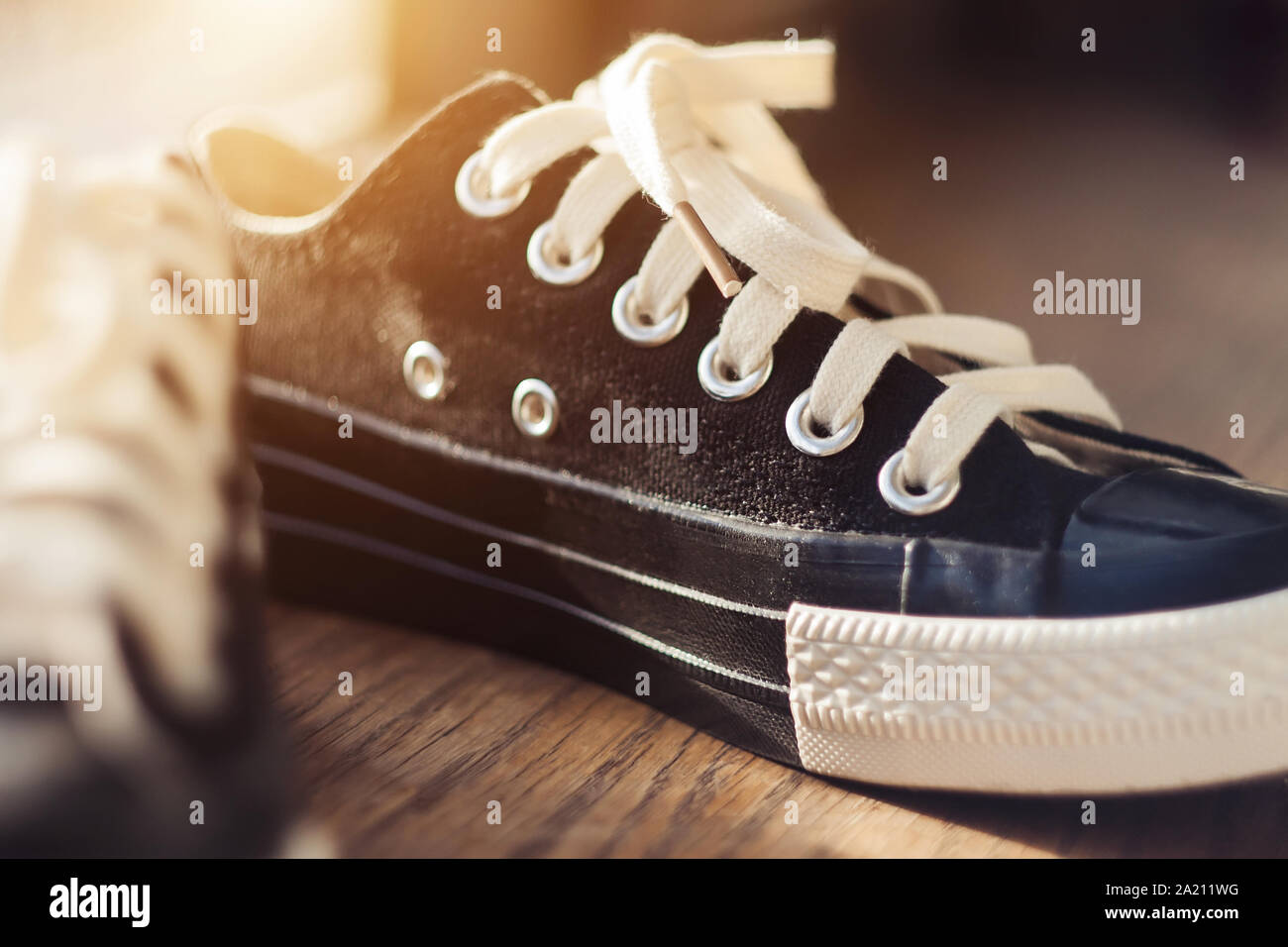 Los nuevos deportes de moda negro zapatillas blancas con cordones de pie en  el suelo de madera, iluminado por la luz solar del verano Fotografía de  stock - Alamy