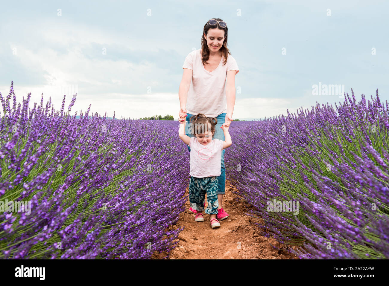 Feliz madre e hija caminando entre campos de lavanda en el verano Foto de stock