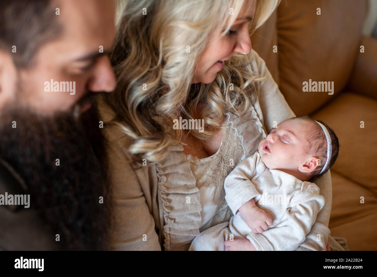 El padre y la madre mirando a su bebé recién nacido chica en el sofá en casa Foto de stock