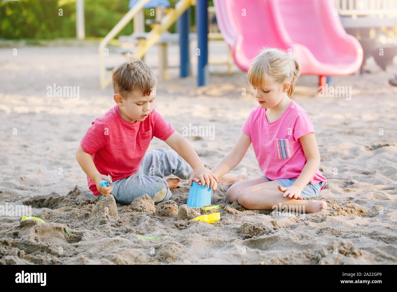Los niños preescolares amigos chico y chica jugando con arena y juguetes en  sandbox en día de verano en el exterior. Infancia feliz estilo de vida. Real  auténtica púb Fotografía de stock -