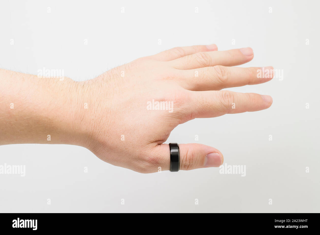 Mano de un hombre blanco vistiendo un grueso anillo negro en el dedo pulgar.  Mano Abierta, la palma hacia abajo. Fondo blanco Fotografía de stock - Alamy