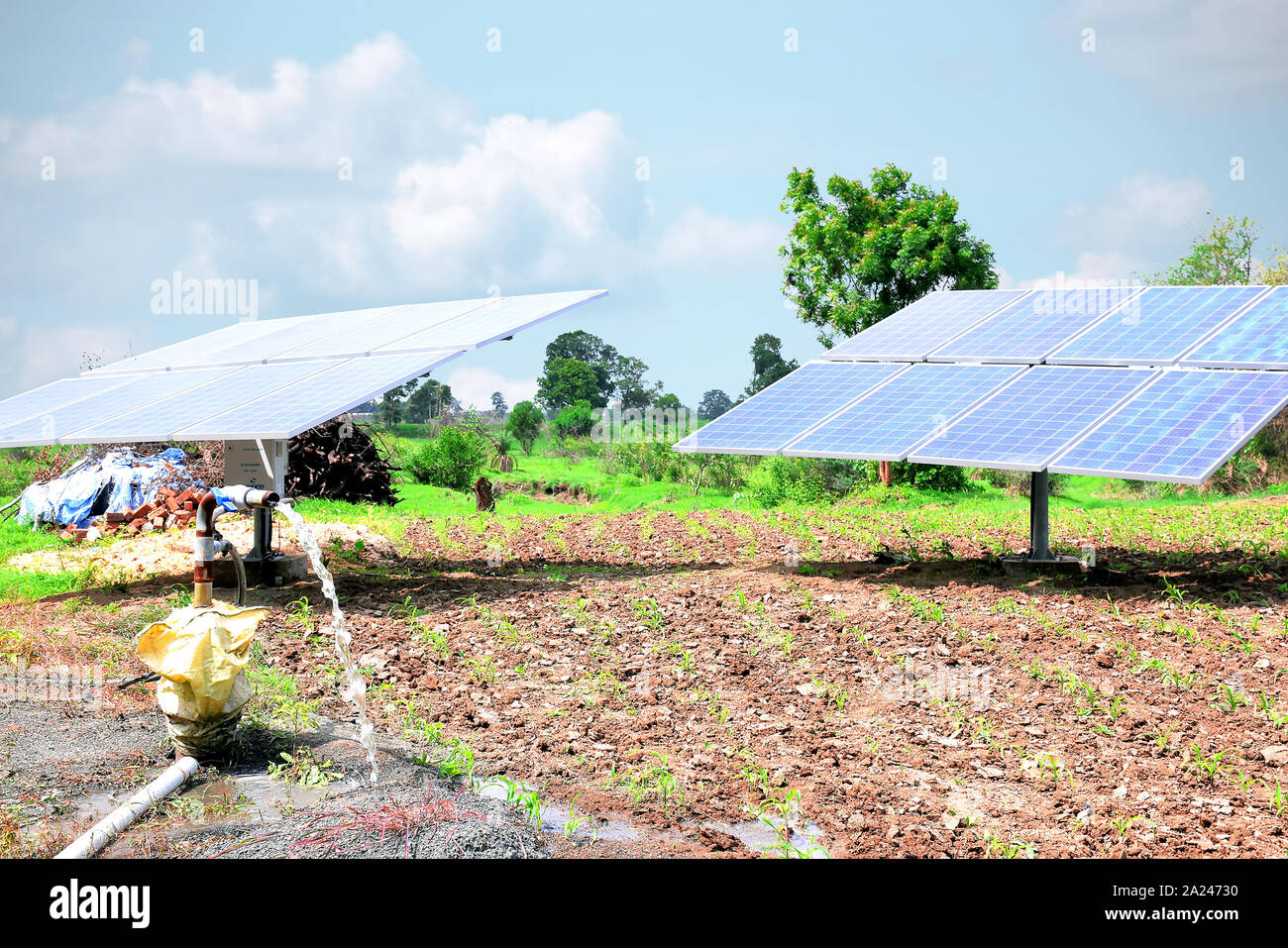 Equipo agrícola para el riego de campo, chorro de agua, detrás de la cual está el panel solar. Foto de stock