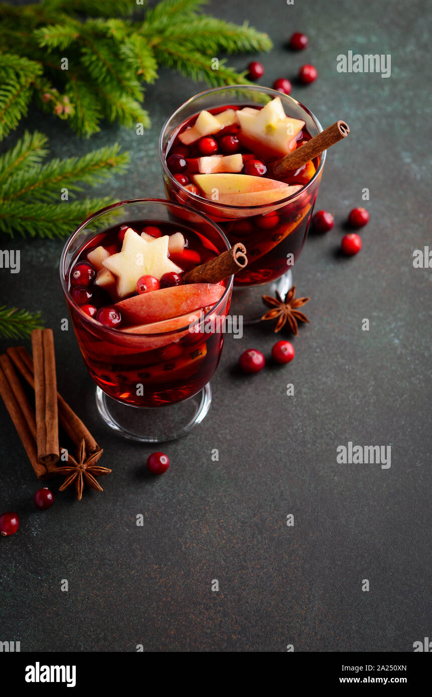 Vino especiado de navidad con manzana, naranja y arándanos. Concepto de vacaciones decorado con ramas de abeto, arándanos rojos y especias. Foto de stock