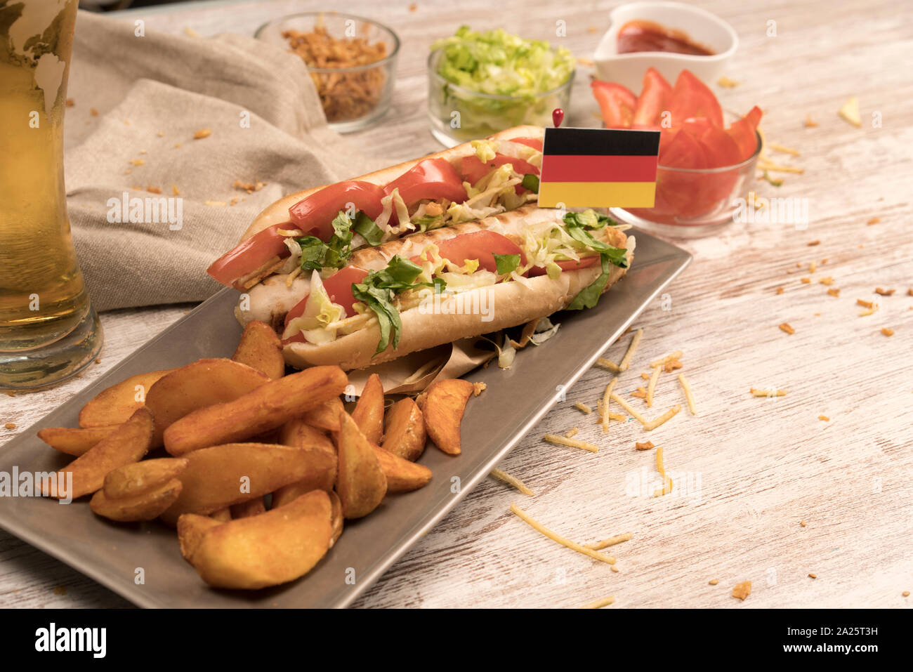 Hot Dog con salchicha blanca casera con diversos condimentos y bandera Alemana en medio plana Foto de stock