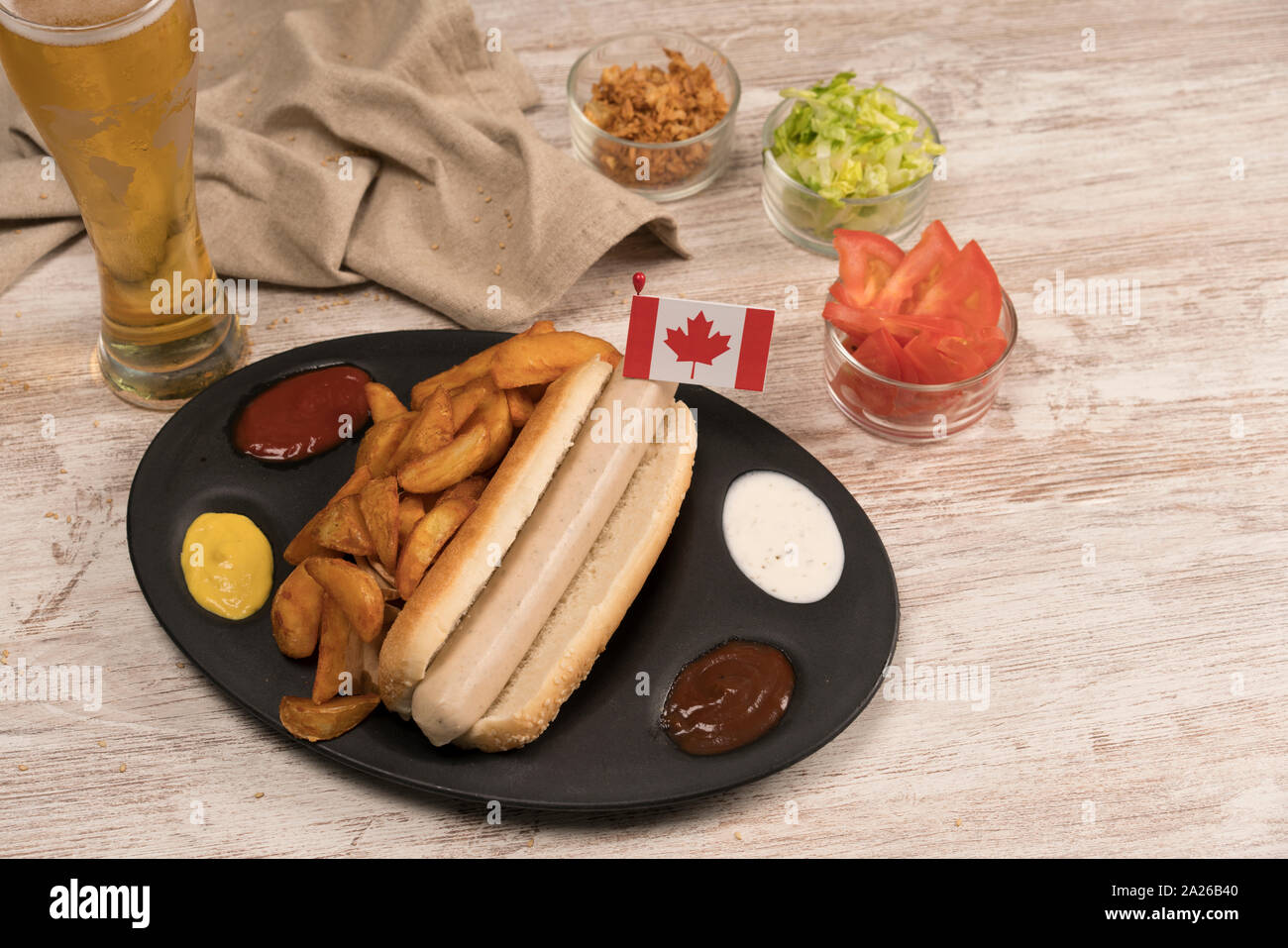 Perro caliente casero con salchichas blancas en bandeja con diversos condimentos y la bandera Canadiense vistos desde arriba Foto de stock