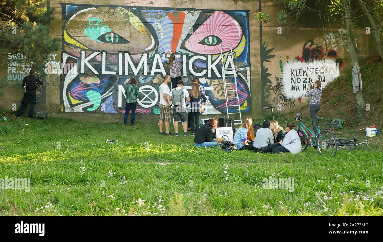 Los activistas personas pinturas y repintado extinción símbolo de rebelión en pared legal para graffiti, demostración de acción contra el cambio climático, la gente Foto de stock