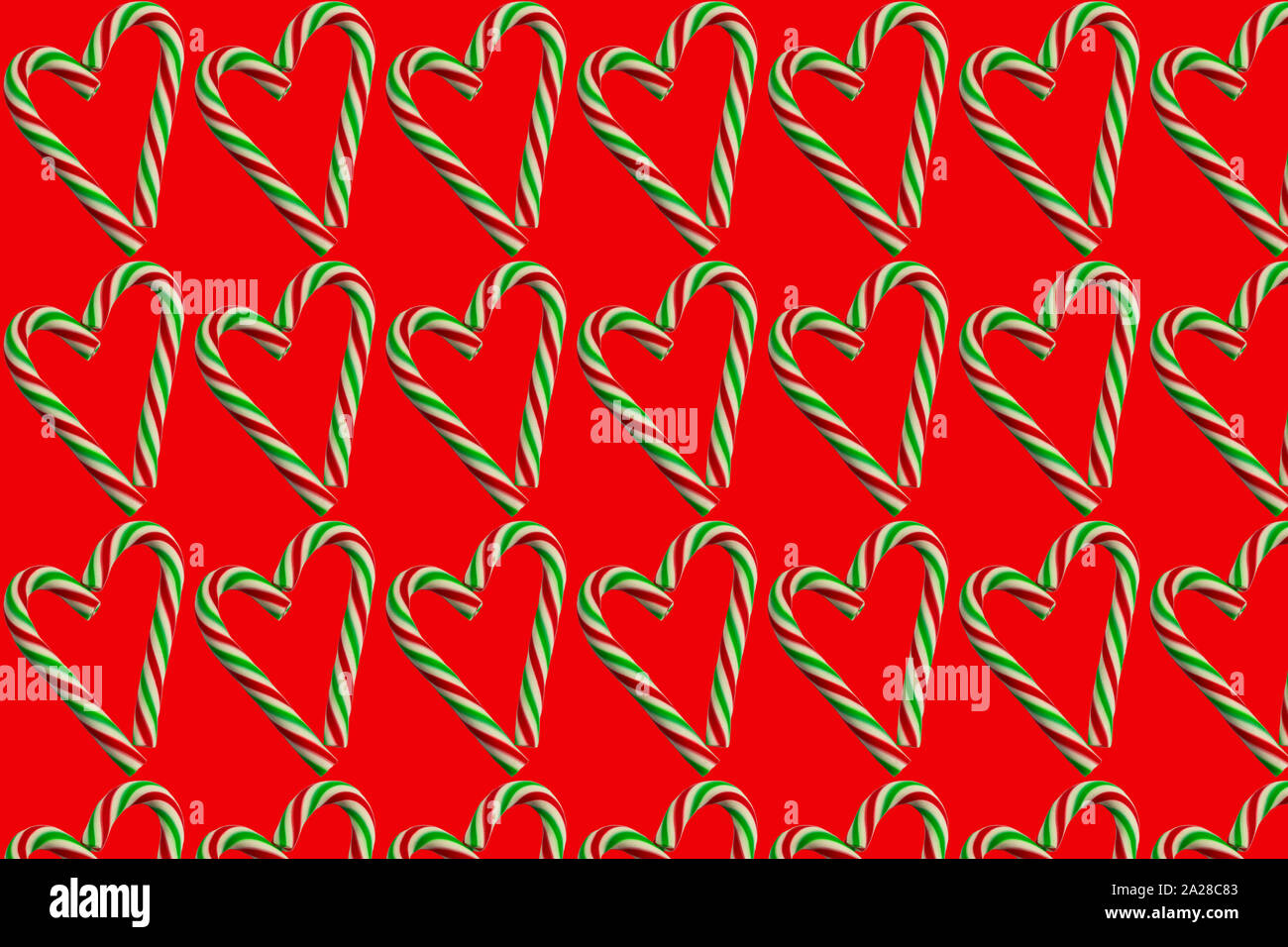 Pequeños corazones de dulces navideños sobre un fondo rojo. Papel de envolver el concepto de patrón sin fisuras, papel tapiz, tejido patrón. Foto de stock