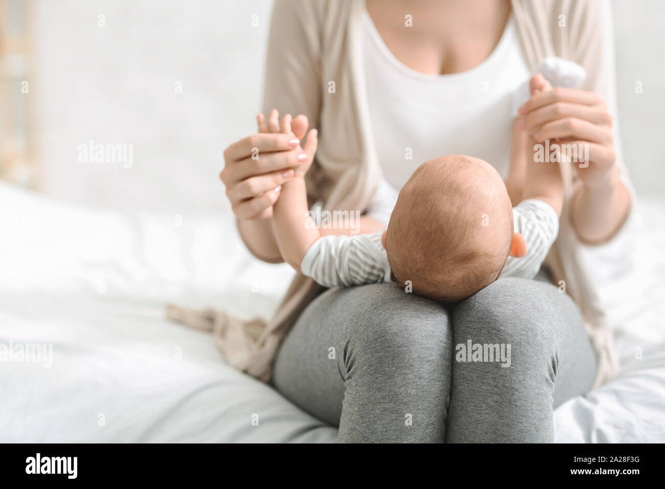 Madre sosteniendo bebé recién nacido sobre el regazo, pegado con su hijo Foto de stock