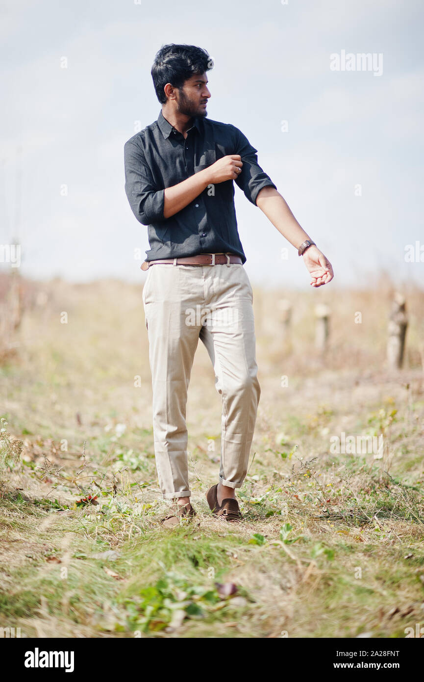 Hombre indio en camisa negra y pantalones beige planteados campo Fotografía de stock -