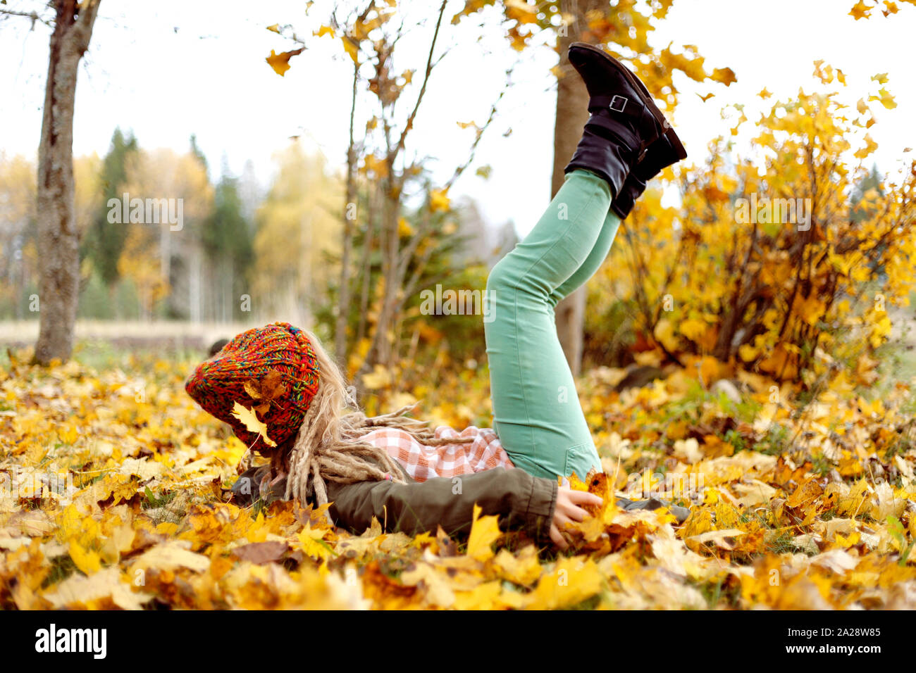 Chica cayó en el amarillo dorado, hojas de arce y se divierten en las hojas de arce en otoño. Foto de stock