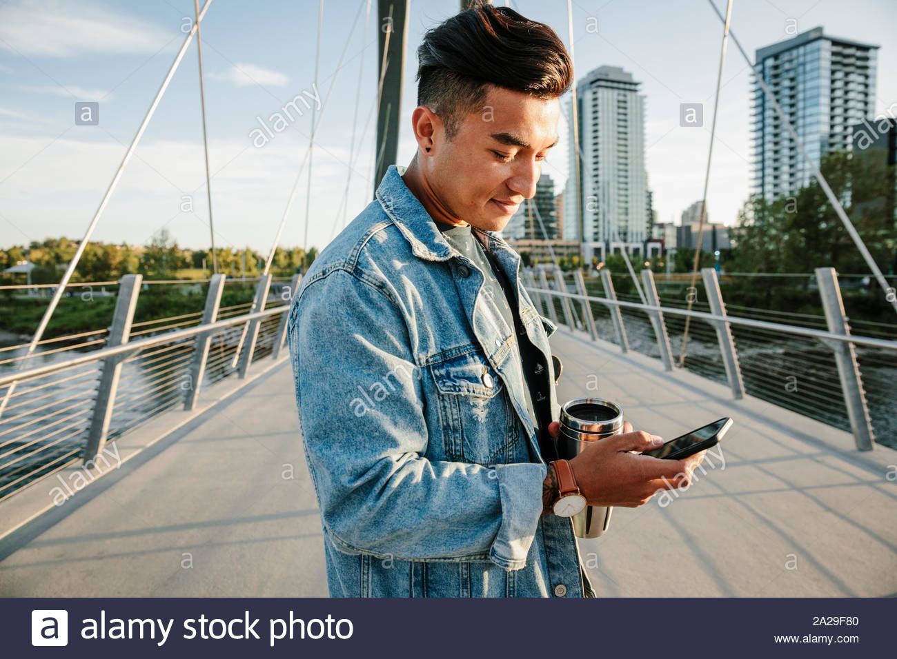 Joven utilizando smart phone en sunny, puente urbano Foto de stock