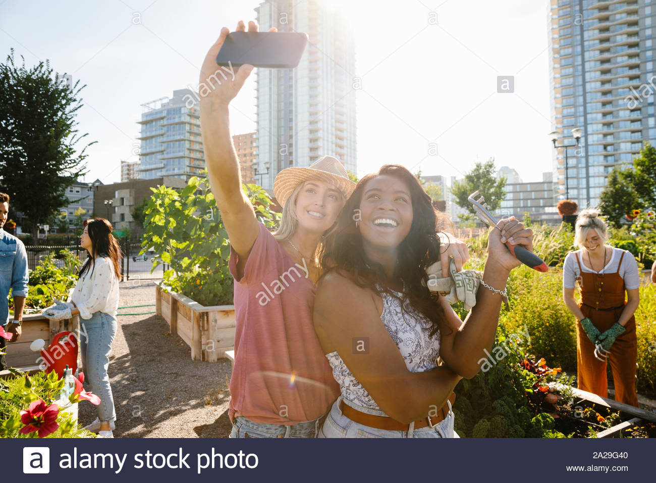 Feliz, confiado a las mujeres jóvenes amigos tomando selfie teléfono con cámara en el soleado jardín, comunidad urbana Foto de stock