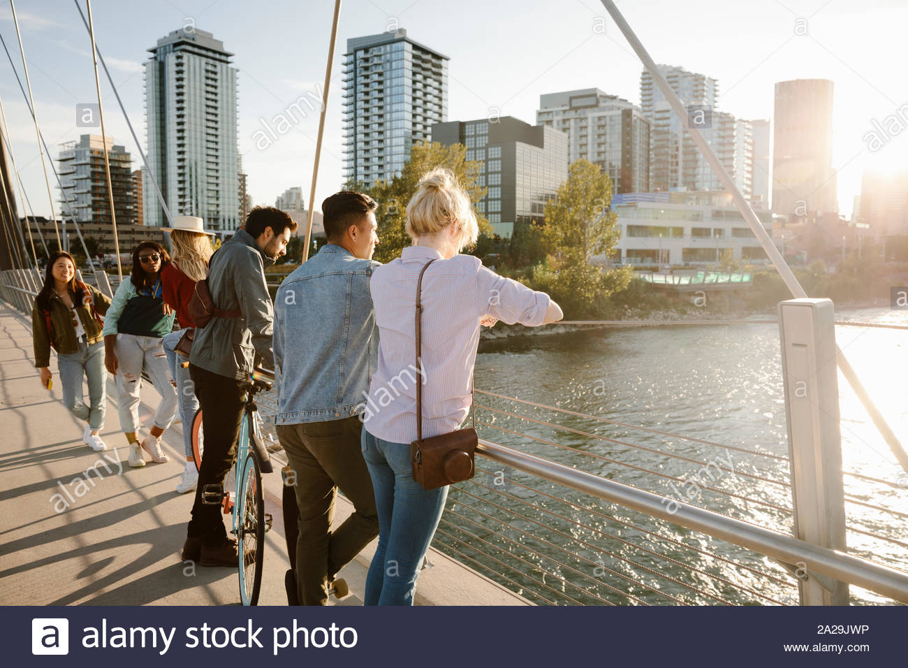 Adultos jóvenes amigos mirando río desde sunny, puente urbano Foto de stock