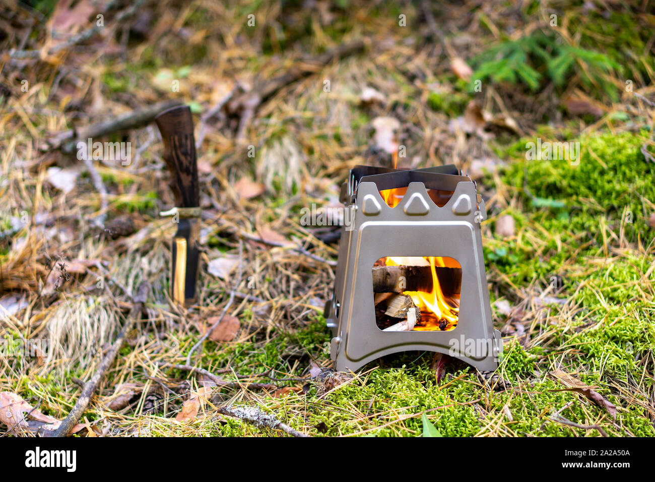 Plegable de la quema de leña para cocinar al aire libre utilizando ramitas como combustible en el fondo de la naturaleza Foto de stock