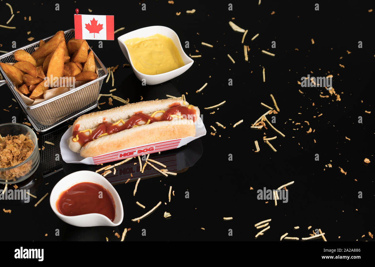 Hot Dog con condimentos, salsas y patatas visto desde arriba en metacrilato negro Foto de stock
