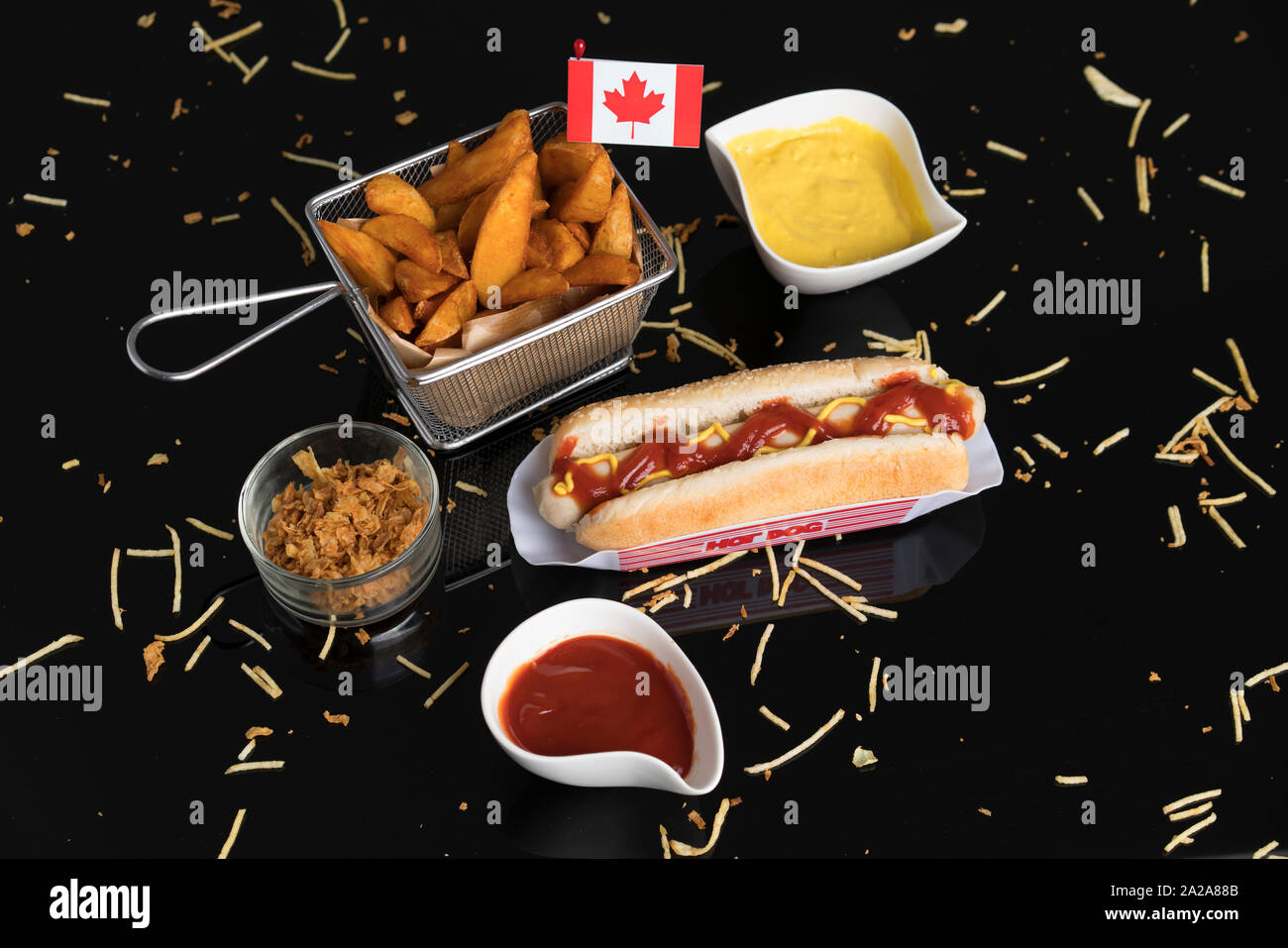 Hot Dog con condimentos, salsas y patatas visto desde arriba con la bandera Canadiense Foto de stock