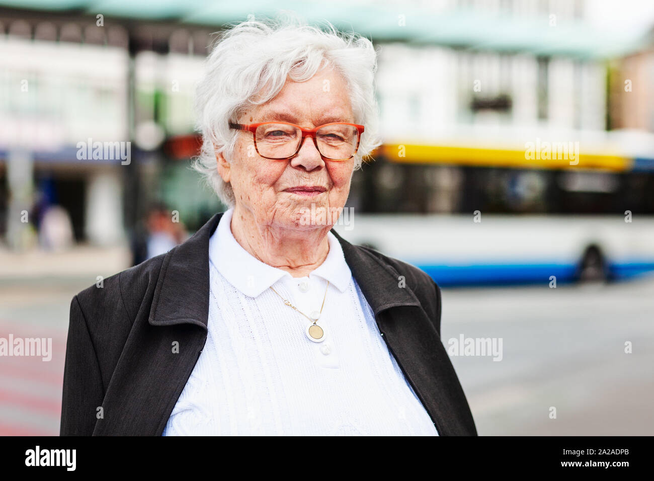 Retrato de mujer mayor de 87 años de edad en la estación de autobuses. Viajes y concepto de estilo de vida activo Foto de stock