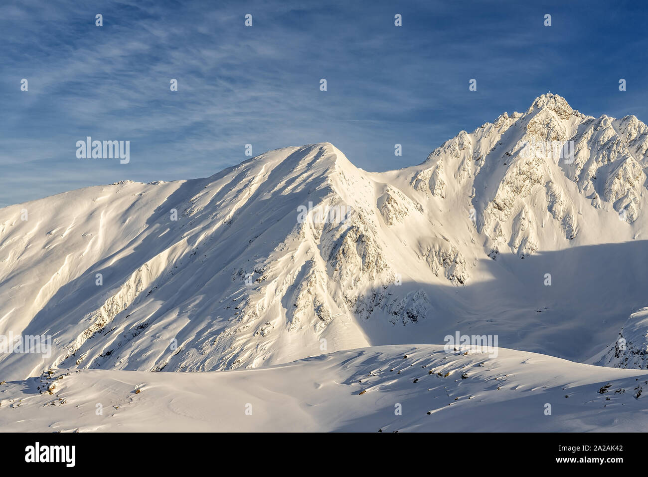 Pintorescos Alpes austriacos picos montañosos cubiertos de capa de nieve en invierno a tiempo cálido atardecer o al amanecer. Azul claro sy en segundo plano. Rocosa natural Foto de stock